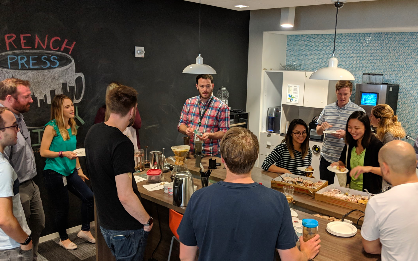 A group of Deloitte consultants around a table full of dixie cups with freshly brewed coffee.